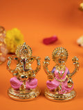 A gold-colored idols of the Hindu deities Ganesha and Lakshmi sitting side-by-side on a golden base, with pink accents on their clothing, against a solid orange background.