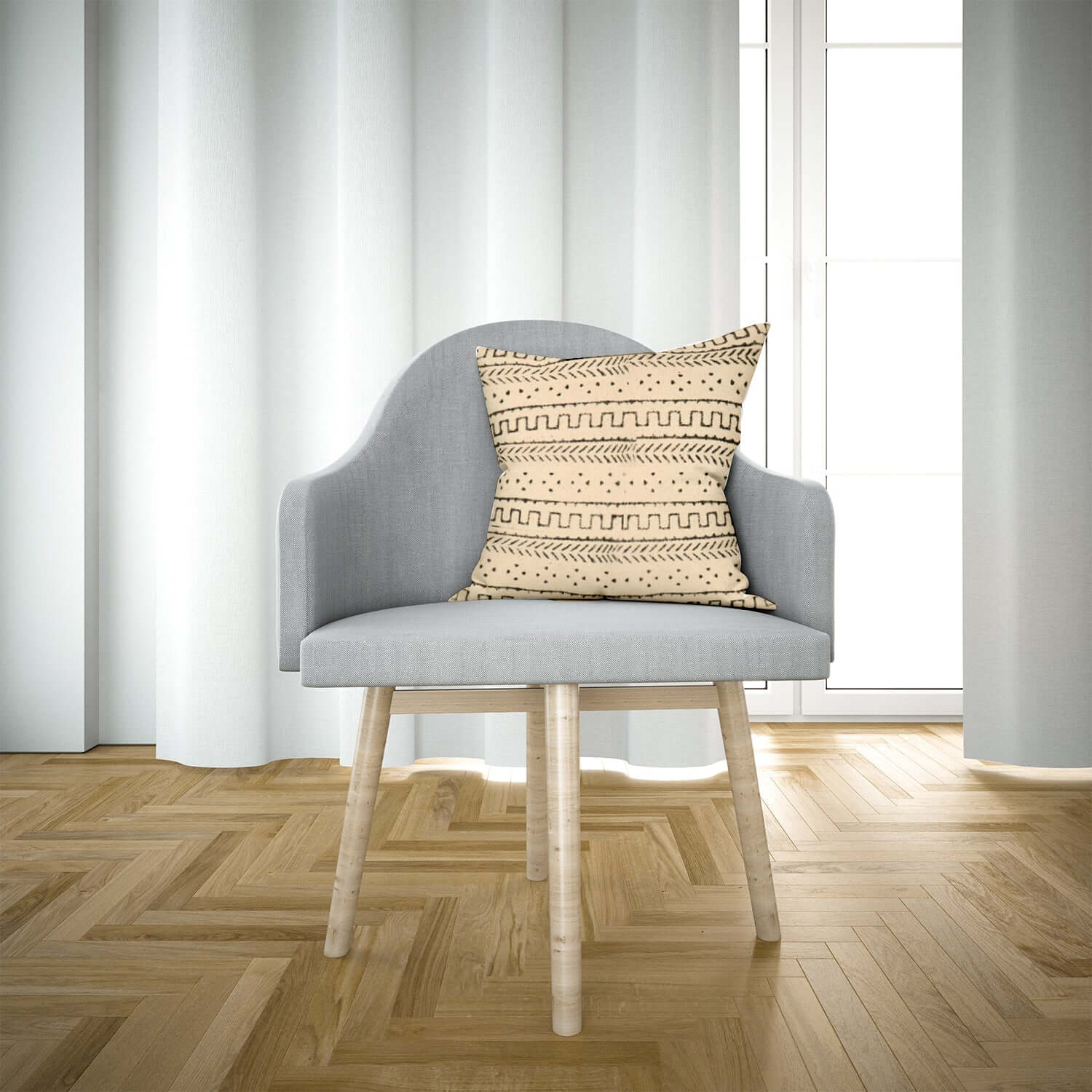A cushion cover with a tribal geometric pattern on a chair in a room with wooden flooring and white curtains.