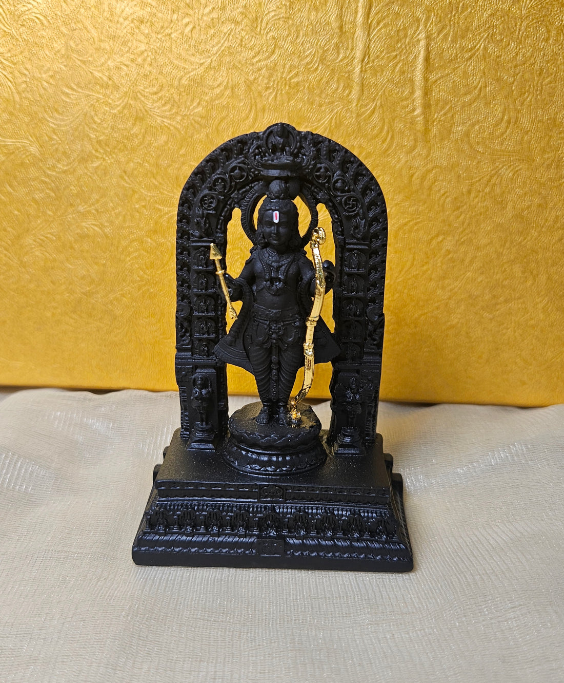 A detailed black polyresin statue of Ram Lala (child Lord Rama) standing on a base, holding a golden bow and arrow, and surrounded by an intricately carved archway.