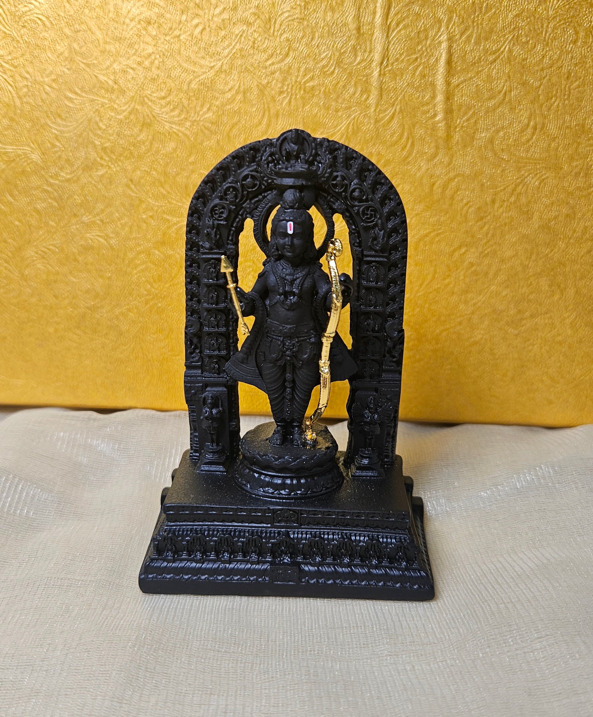 A detailed black polyresin statue of Ram Lala (child Lord Rama) standing on a base, holding a golden bow and arrow, and surrounded by an intricately carved archway.