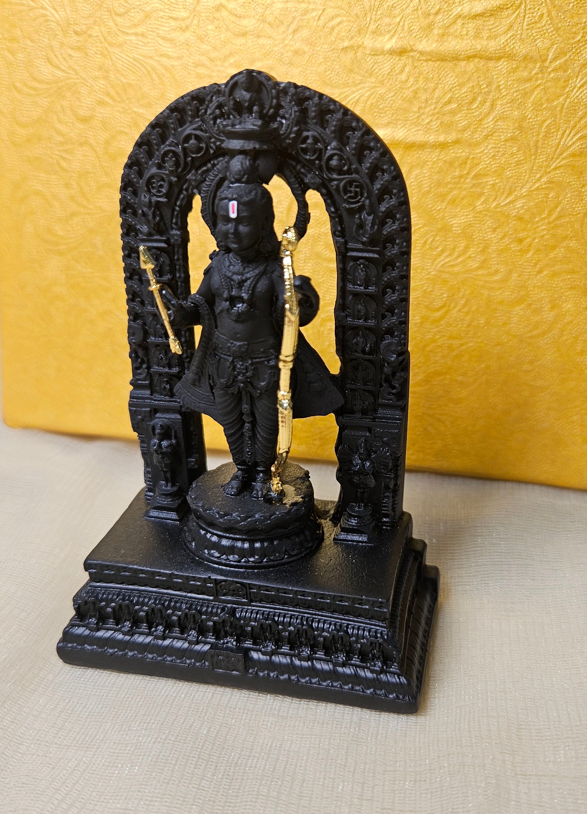 Black stone Ram Lalla statue representing the child form of Lord Rama, with golden weaponry