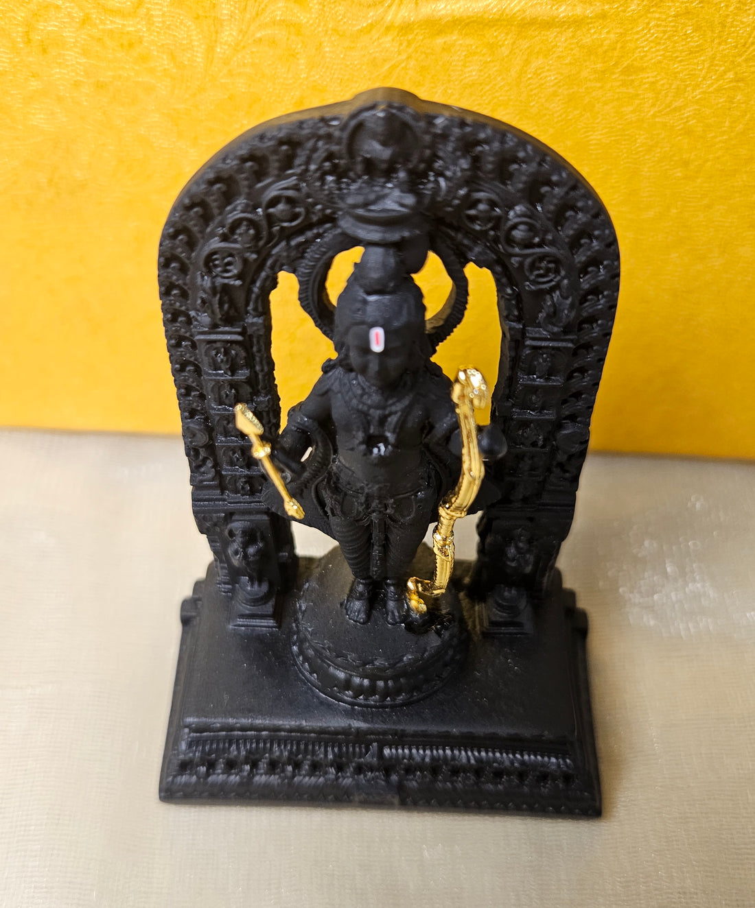 A detailed black polyresin statue of Ram Lala (child Lord Rama) standing on a base, holding a golden bow and arrow, and surrounded by an intricately carved archway.