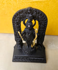 A black idol of Ram Lalla (child Lord Rama) standing on a lotus, holding a golden bow and arrow, with an ornate archway behind, possibly from the Ayodhya Ram Mandir.