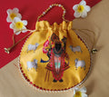 A yellow Shreenathji Potli Bag made of Gaji silk, featuring the deity Shreenathji surrounded by cows, with a pearl-beaded handle and drawstring closure.