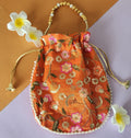 A Orange floral design potli bag with golden embroidery and a drawstring closure