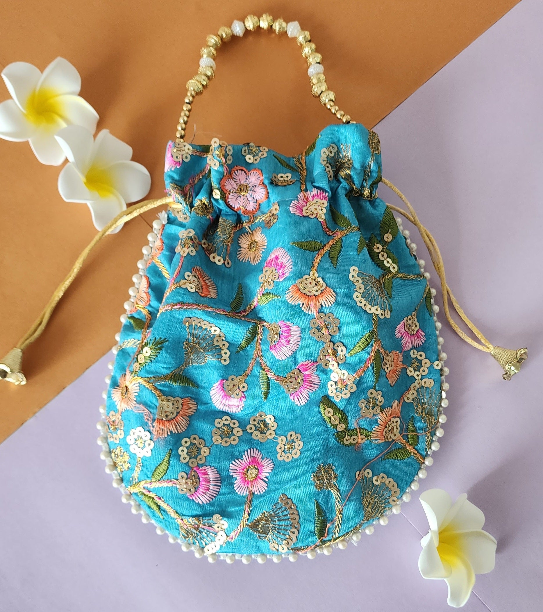 A Blue floral design potli bag with golden embroidery and a drawstring closure