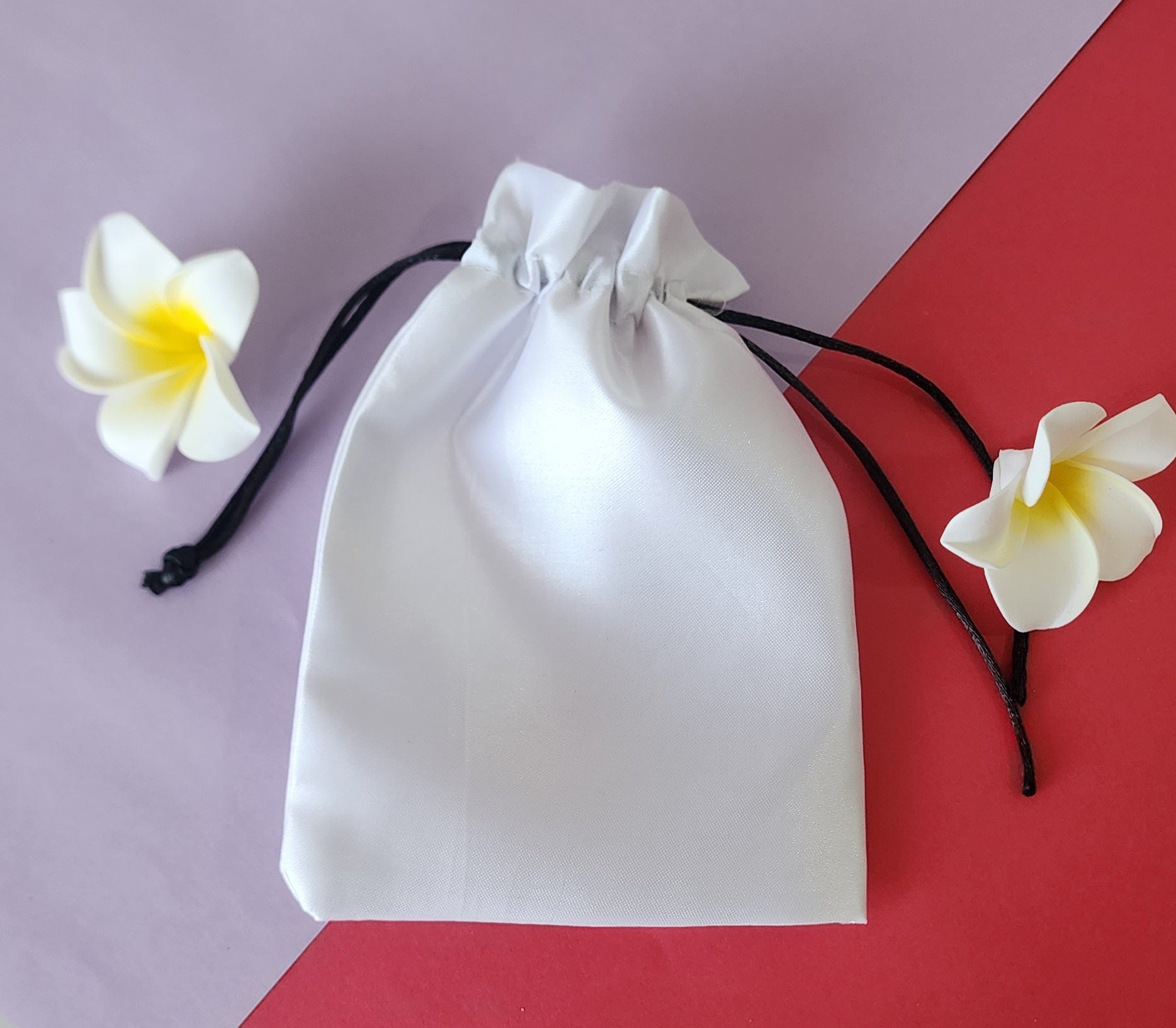 White Potli bag in plain color with flowers around it