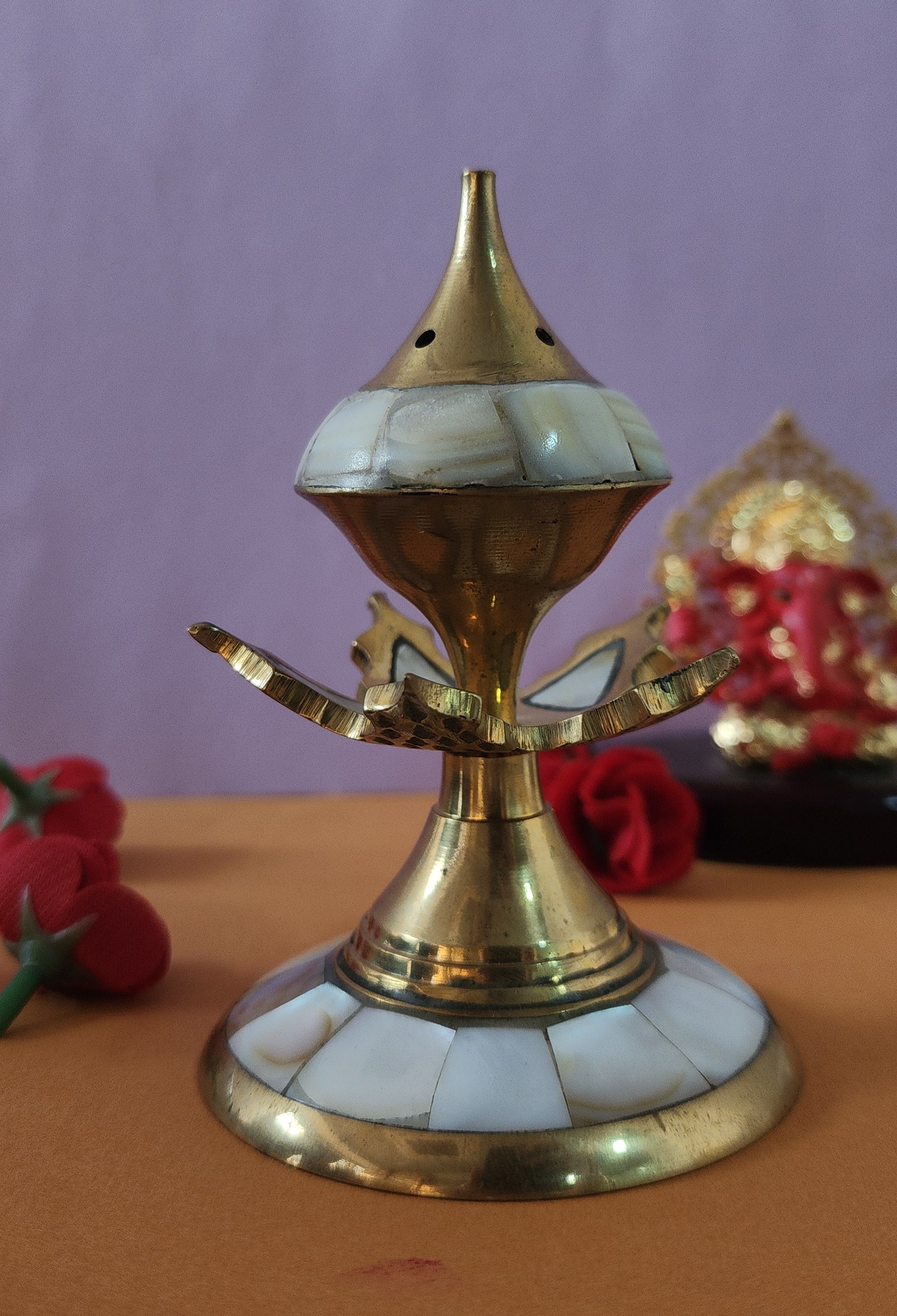 flower shape Incense Burner with red flowers behind it