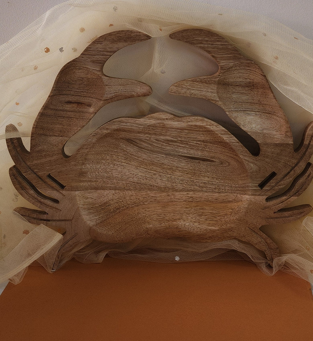 A wooden serving platter designed in the shape of a crab, with a rustic finish and natural wood colors.