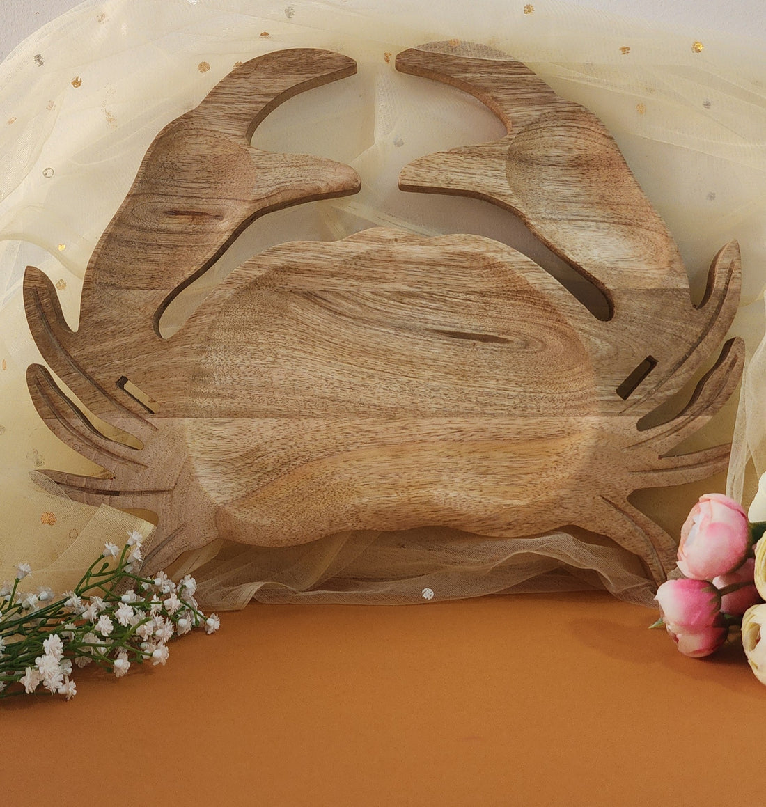 A wooden serving platter designed in the shape of a crab, with a rustic finish and natural wood colors.