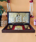 A gold-plated pocket temple featuring Lord Balaji, Goddess Lakshmi, and Goddess Padmavati, along with Charan Paduka, housed within a wooden framed box.