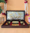 A gold-plated Lord Shiva Pocket Temple, featuring a central idol surrounded by smaller deities or symbols, displayed in an open wooden box with a red velvet interior and two additional gold-colored plaques with