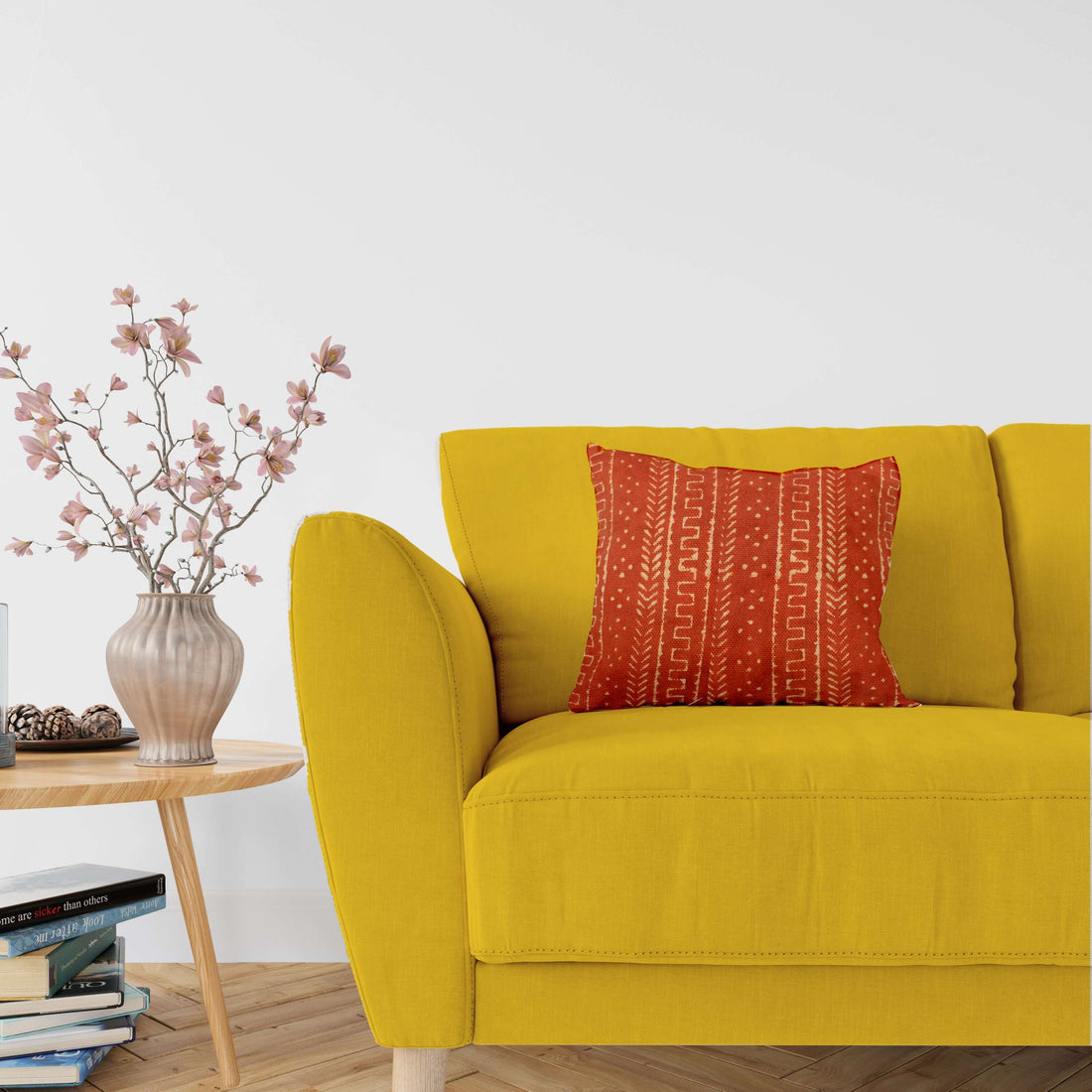 A cushion cover with a rust mudcloth block print pattern, displayed on a yellow sofa.