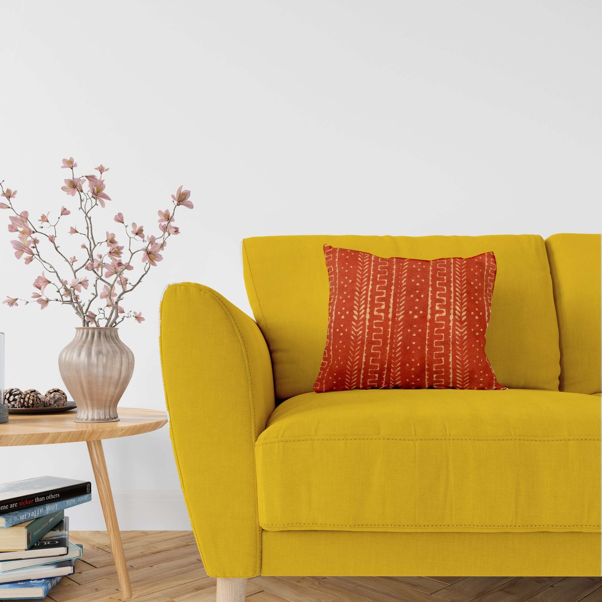 A cushion cover with a rust mudcloth block print pattern, displayed on a yellow sofa.