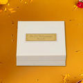 A white rectangular box with a golden plaque on its lid, inscribed with the Sanskrit mantra