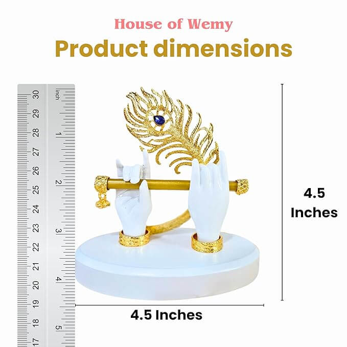 A close-up of a white, gold-plated statue featuring Lord Krishna's hands holding a golden flute with a peacock feather, displayed alongside a ruler indicating its 4.5-inch dimensions, under the "House of Wemy" brand.