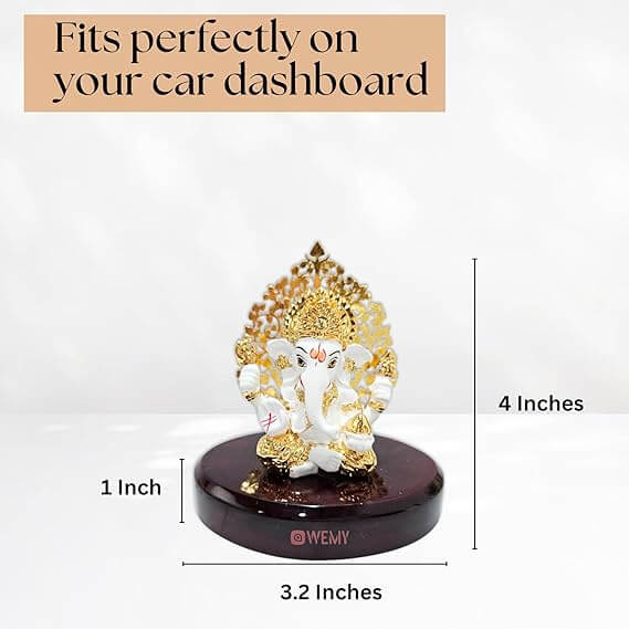 A white and gold Ganesha idol, labeled 'WEMY,' displayed on a dark wooden base with dimensions shown: 4 inches tall, 1 inch wide for the idol's base, and 3.2 inches wide for the entire wooden base. Text overlay states 'Fits perfectly on your car dashboard.
