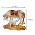 A detailed, decorative golden and white Kamadhenu cow and calf idol, approximately 3 inches in both height and length, as indicated by visible text and measurement lines.