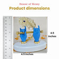 A close-up of a Krishna Hand Flute Statue on a white base, featuring two blue hands holding a golden flute, adorned with a golden peacock feather with a blue gem. A ruler on the left side and text on the right indicate the statue's height as 4.5 inches. The top of the image also shows 'House of Wemy Product dimensions'.
