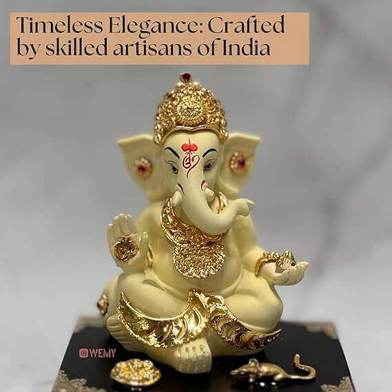 Ornate Ganesha idol in creamy white with gold accents, seated on a black base with small offerings, accompanied by text 'Timeless Elegance: Crafted by skilled artisans of India'.