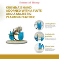 Product advertisement for 'House of Wemy Krishna's Hand Idol,' featuring a blue-colored statue of Lord Krishna's hands holding a flute and adorned with a peacock feather, with text highlighting 'Lasting Grace,' 'Crafted with precision,' and a 'Sturdy base.'