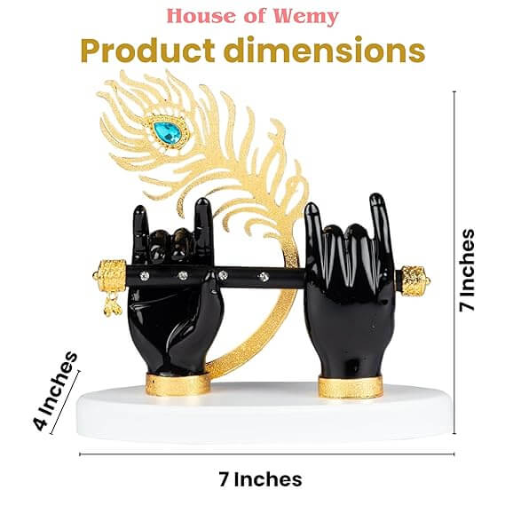 A decorative idol by "House of Wemy" featuring a pair of black hands holding a black flute, with a golden peacock feather adorned with a blue jewel, all mounted on a white base. The image also displays text indicating "Product dimensions" as 4 inches, 7 inches, and 7 inches.