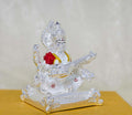 An image of a silver-plated idol of the Hindu goddess Saraswati seated and playing the veena, with intricate details and accents of red and gold.