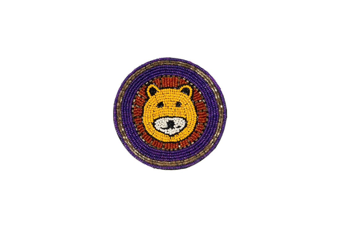A collection of four Beaded Coasters - Safari Theme on a rustic wooden surface. Each coaster features the face of a different beaded animal: a yellow lion, a light blue elephant, a brown tiger, and a dark brown bear.