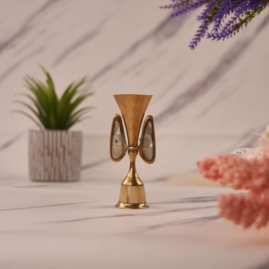 A single candle holder made of brass with mother of pearl inlays, displayed against a home décor background.