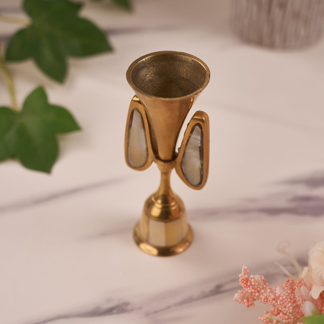 A single candle holder made of brass with mother of pearl inlays, displayed against a home décor background.