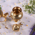 open brass lota with flowers around it