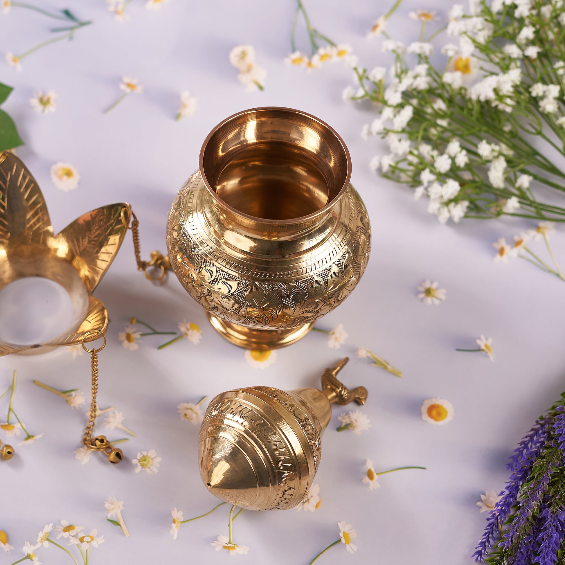 open brass lota with flowers around it