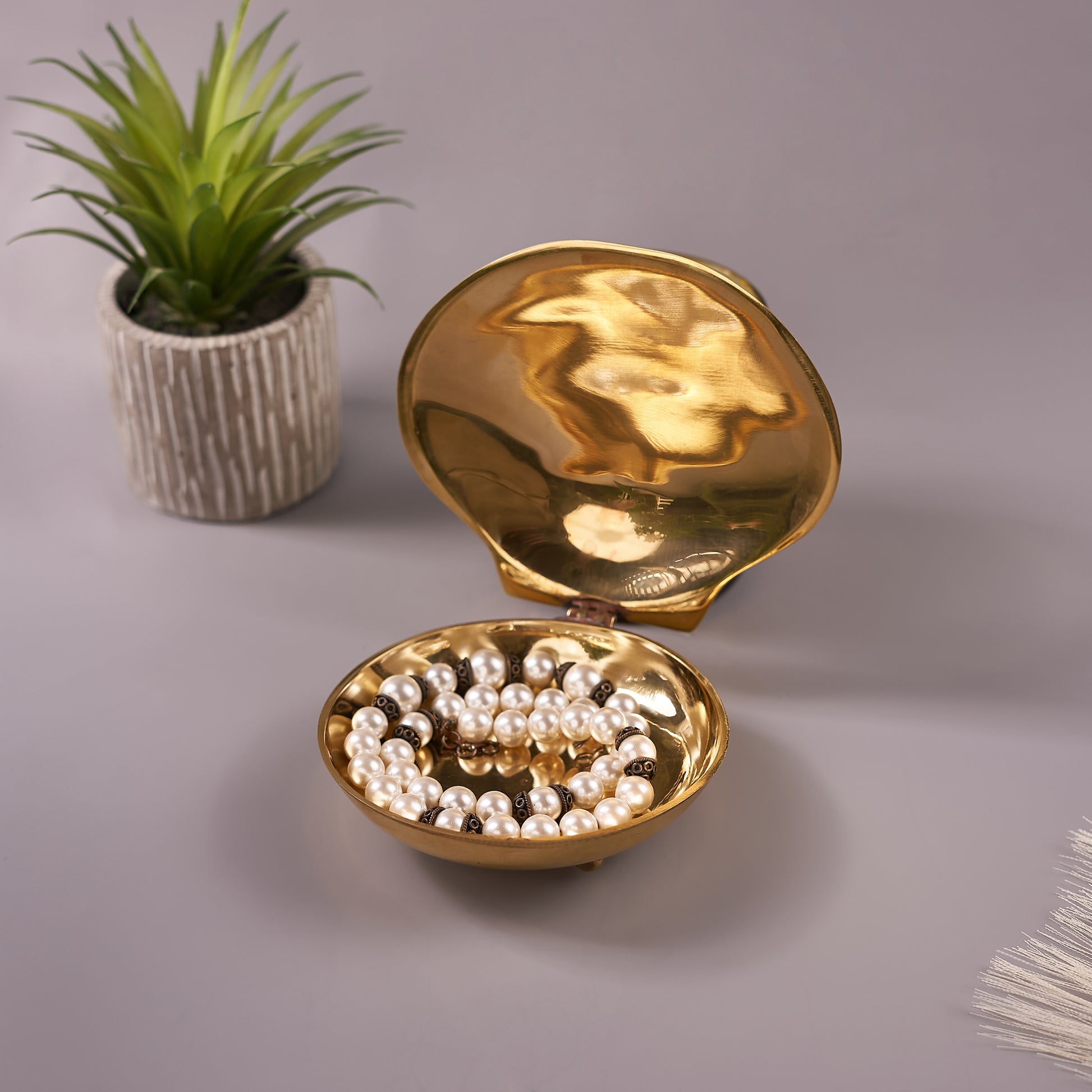 open seashell shaped jewelry box with moto mala in it