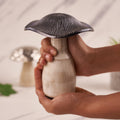 A silver mushroom-shaped decorative carring on hands