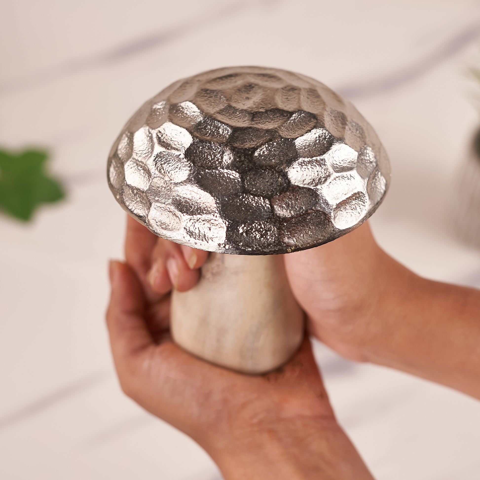 A decorative mushroom with a silver cap in the hands