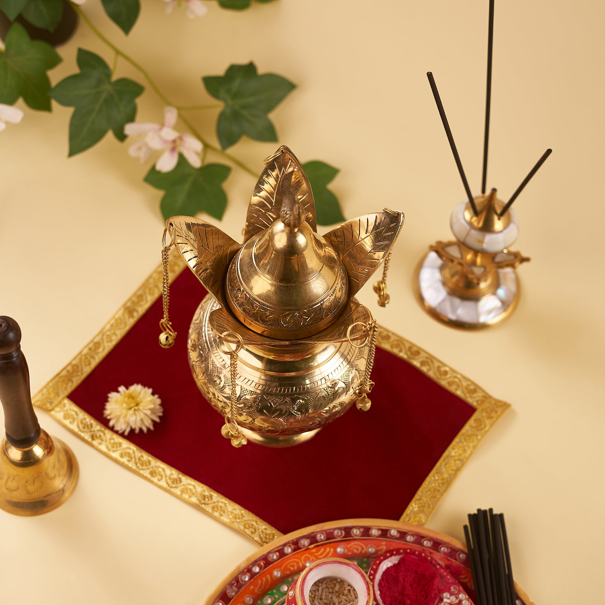 Brass lota on the red chariot with pooja thali and bell around it