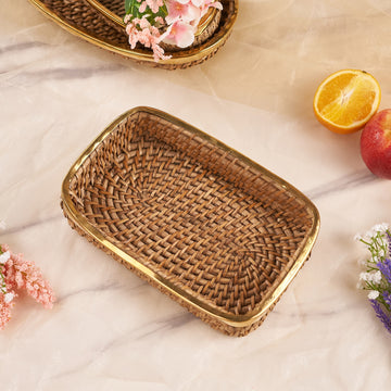A rectangular rattan tray displayed on a neutral background, accompanied by fruits and flowers.