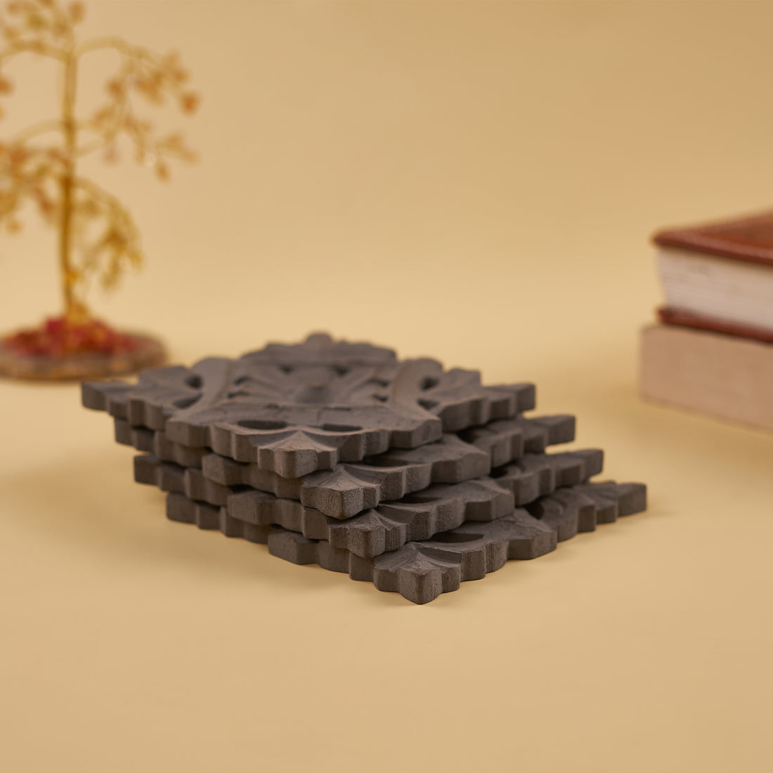 A set of four dark grey wooden coasters with a geometric pattern, displayed on a plain background.