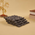A set of four dark grey wooden coasters with a geometric pattern, displayed on a plain background.