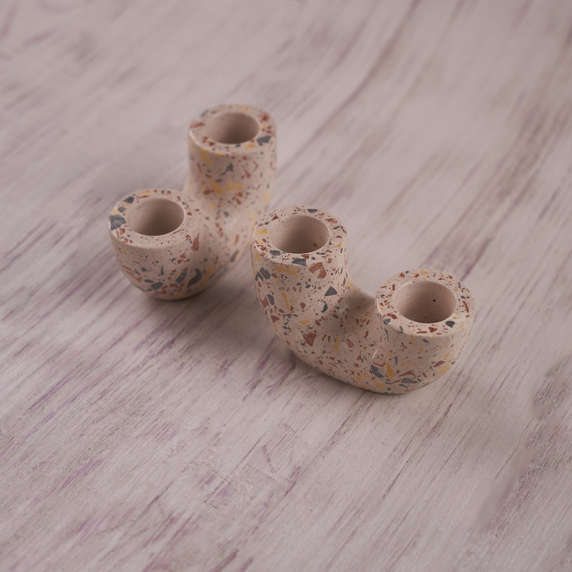 A pair of U-shaped, terrazzo-style Ceramic Curve Candle Holder Set of 2 is displayed on a light wooden background. The speckled design features small, colorful flecks, and each holder has two openings for taper candles.