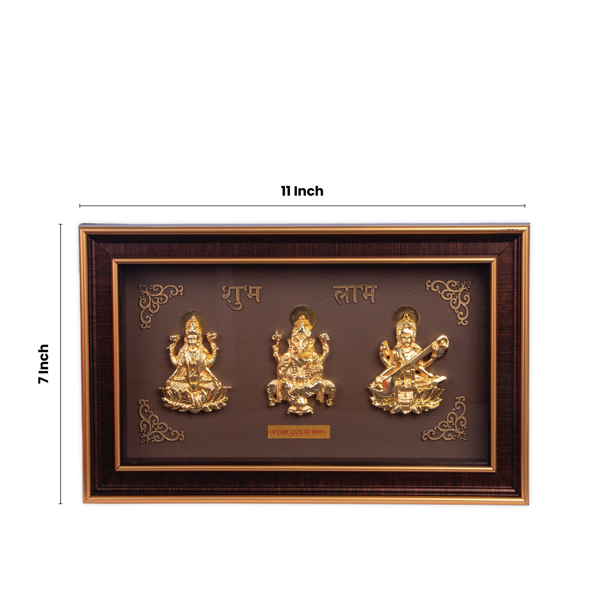 A rectangular brown and gold framed art piece, 7 by 11 inches, featuring three golden, embossed Hindu deities: Goddess Lakshmi on the left, Lord Ganesha in the center, and Goddess Saraswati on the right. Above the deities, the words "शुभ" (Shubh) and "लाभ" (Labh) are written in golden Hindi script. The frame has decorative golden accents on the corners.
