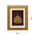 A golden-framed art piece featuring a metallic or gold-plated idol of Lord Ganesha seated on a golden leaf, possibly a Peepal leaf, set against a maroon background within the frame. The frame's dimensions are indicated as 8 inches (height) and 9.5 inches (width).