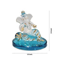 A small, transparent Ganesha idol with blue accents, sitting on a round blue base. The idol features intricate details and appears to be made of crystal or glass, measuring approximately 2.5 inches in height and width.
