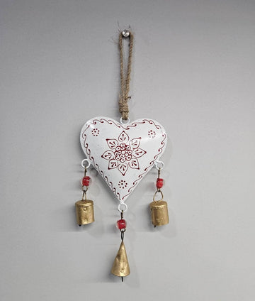 A hand-painted white metal chime with intricate designs, hanging from a jute string, with gold-colored bells attached.