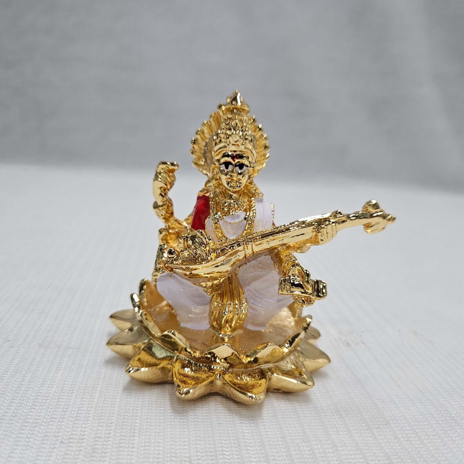 Intricately crafted gold-plated idol of Goddess Saraswati, patron of knowledge and arts, playing her veena.