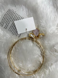 A set of two gold-colored brass metal bangle bracelets with semi-precious stone accents, displayed on a white furry surface.