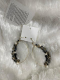 A pair of black and grey finish crystal bead wrapped earrings displayed on a white fuzzy surface
