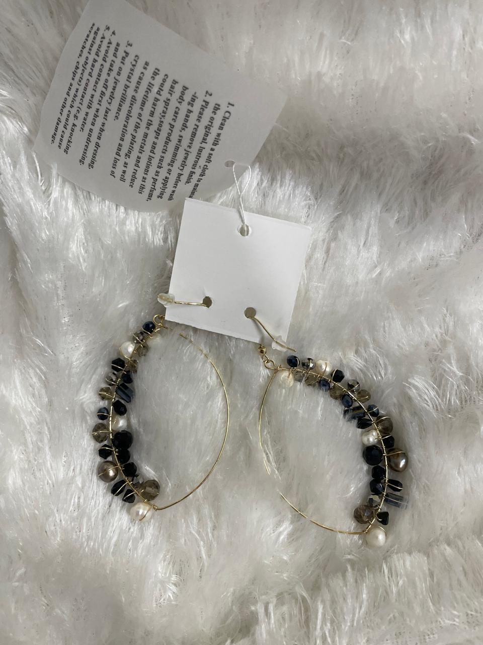 A pair of black and grey finish crystal bead wrapped earrings displayed on a white fuzzy surface
