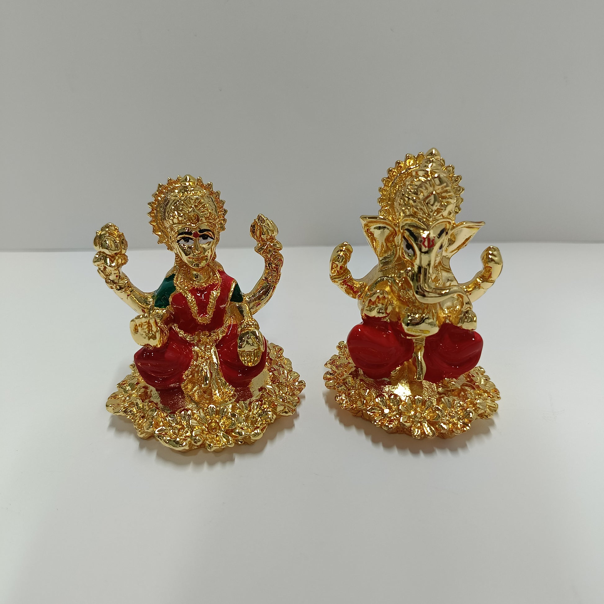 The image displays a set of gold-plated idols featuring the Hindu deities Goddess Lakshmi and Lord Ganesha.