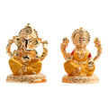 Golden idols of Lord Ganesha and Goddess Lakshmi sitting side-by-side on decorative bases.